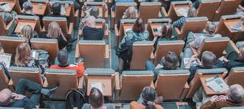 Bachelor Berufspädagogik Ausschnitt eines Hörsaals mit Einzelsitzen von oben. Der Härsaal ist mäßig bis gut gefüllt.